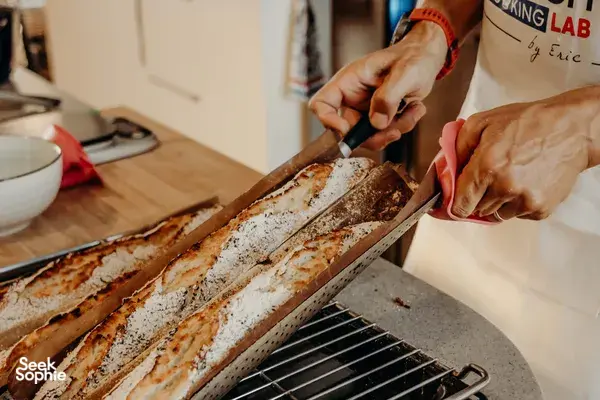French baguettes ready on a tray as hands cut fresh loaves in a cosy Singapore loft — workshops in Singapore