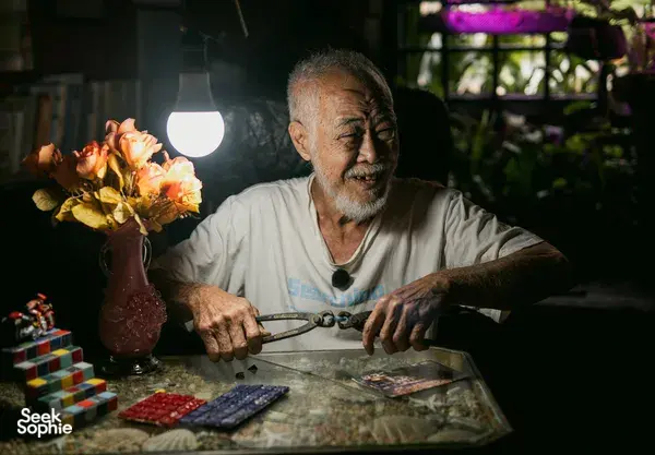 Pria sedang memeriksa kertas dan benda-benda di atas meja di ruangan dengan pencahayaan lembut, untuk kisah apartemen sewa Hidden Heritage dan hidden gems Singapura