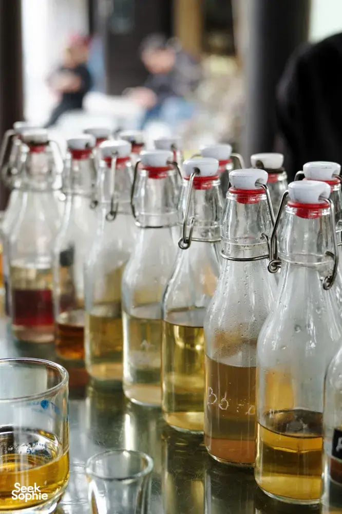 Bottles of local amber drinks and oils on display at a dawn Hoi An market stop during a motorbike trade tour