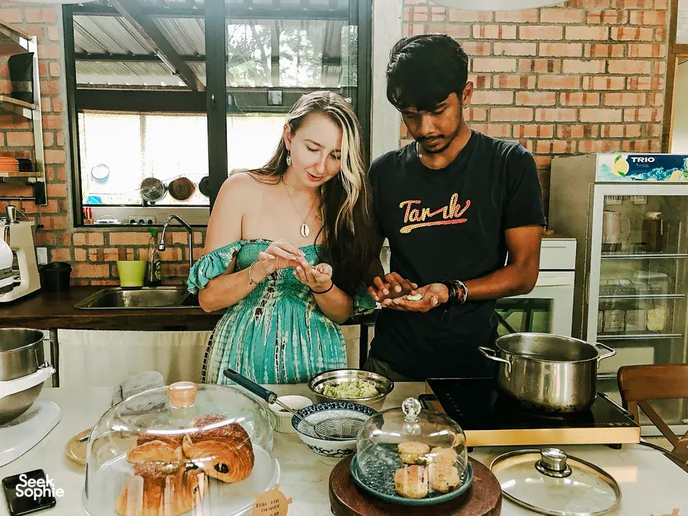 Farmhouse cooking lesson in Langkawi as two guests prepare Malaysian comfort food with herbs and pots in a brick kitchen