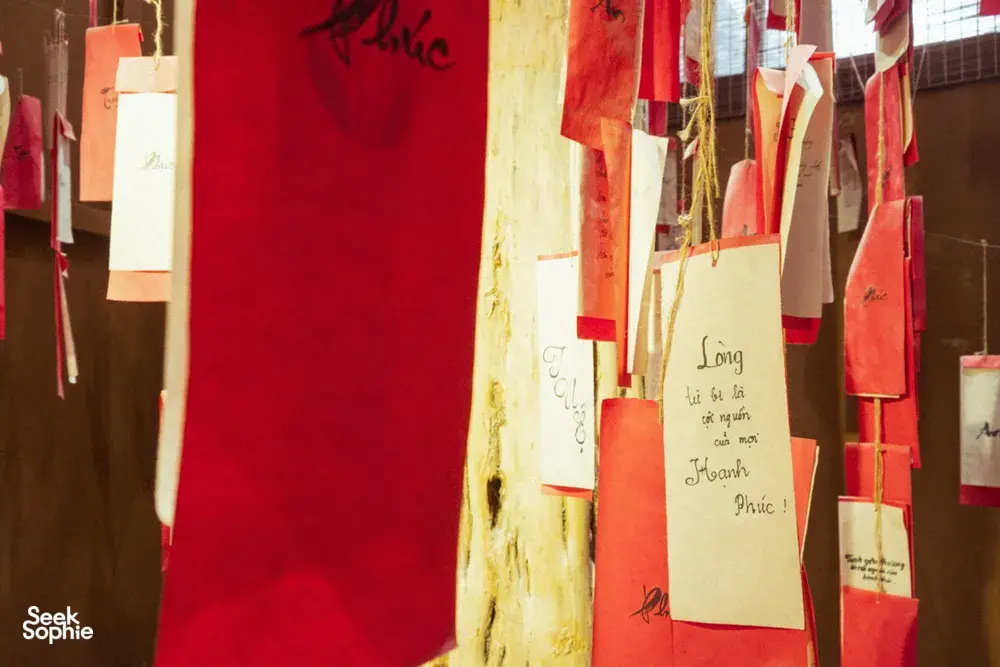Hanging red and gold gift bags with Vietnamese writing inside a shop for an agarwood tour in Hanoi