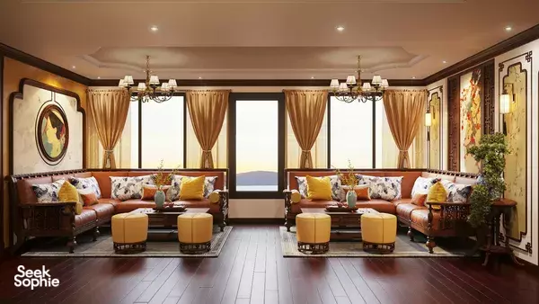 Cycad Cruise cabin lounge with curved sofas, ottoman seating and floor-to-ceiling windows with golden light, on a journey to Halong Bay
