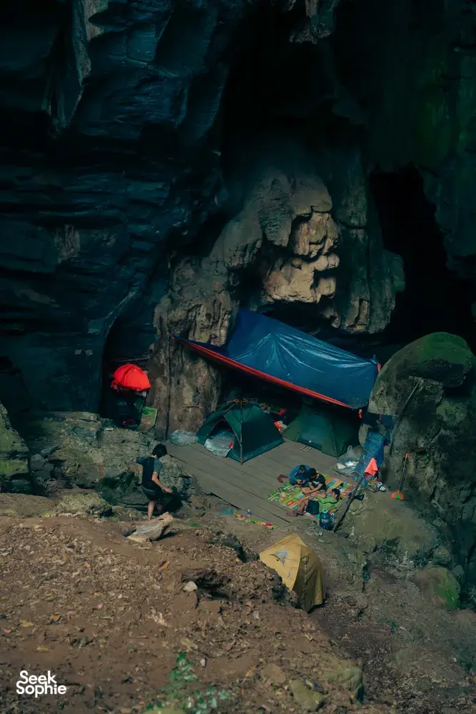 Campsite inside Phong Nha-Kẻ Bàng cave with tents and travellers resting on rough ground on a Greenland Tours trip