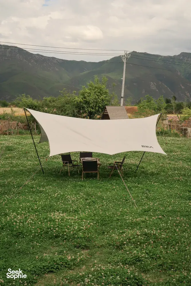 White shade sail over chairs in the Seeker Yunnan Coffee Estate garden, overlooking mountains near Lijiang in Yunnan