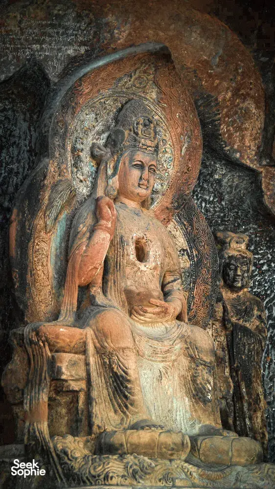 Close-up patung Buddha duduk berwarna di dalam dinding gua batu, gua Buddha Shaxi di eco retreat Dali