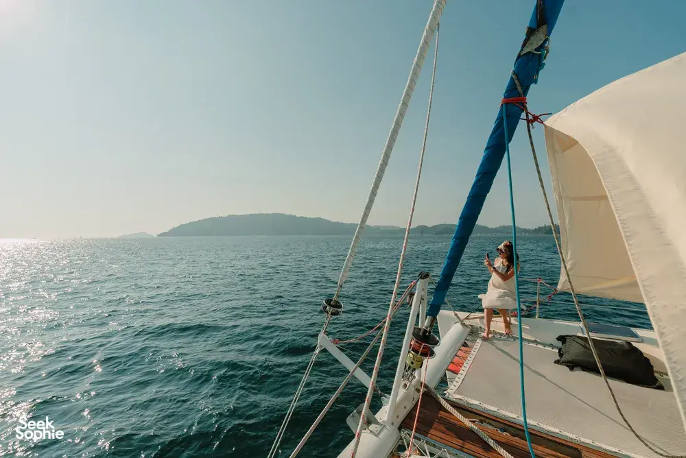 Cosy sailing on a catamaran from Kota Kinabalu, with a person on deck watching the waves under the sail rigging