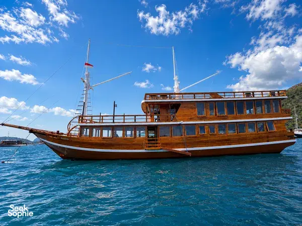 Wooden phinisi sailing on choppy waters under a blue sky on a 3D2N Komodo cruise with La Famille in Labuan Bajo