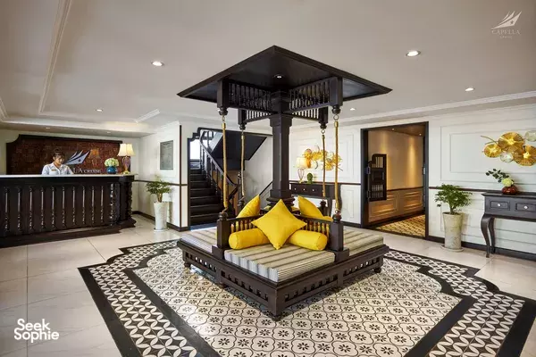 Lyra Cruise Collection lobby in Halong Bay, with a reception desk, patterned rug and staircase, plus a concierge at the bar