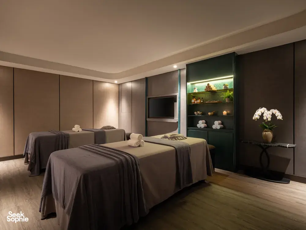 Elegant onboard cabin on Doris Cruise with twin beds, ambient lighting, and a stocked minibar display for Halong Bay 2D1N comfort