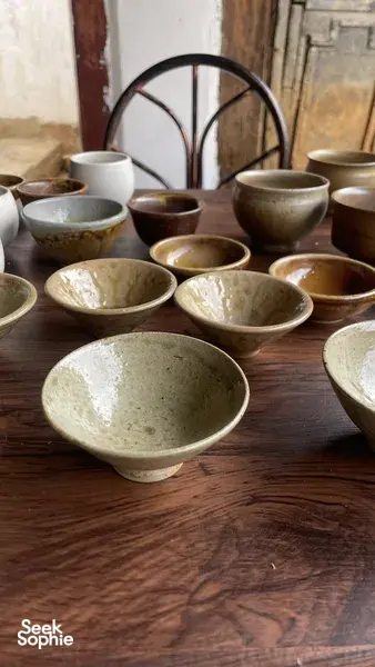 Handmade ceramic bowls and small cups lined up on a wooden table inside an ancient pottery home in Shangri-La, Yunnan