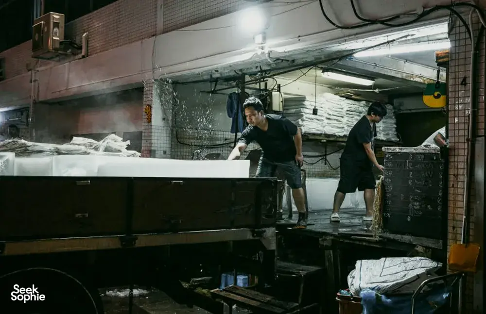 Pemandu Hidden Heritage memimpin melewati lorong belakang yang remang-remang di pelabuhan ikan Jurong, Singapura, sementara para pekerja memilah persediaan