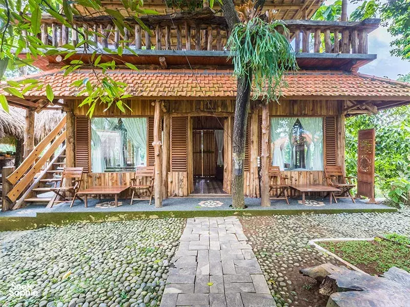 Wooden meditation pavilion with draped curtains and stone walkway at Omunity Bali retreat in Bali