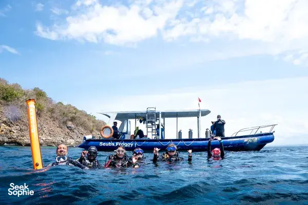 Divers bobbing in the sea beside a dive boat during Lombok Pink Beach 2 Fun Dives in Lombok under a bright sky