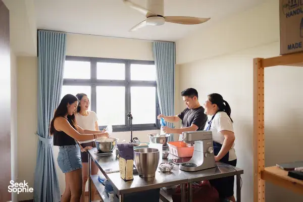Participants shaping shio pan dough beside mixers at a communal table, in a bright kitchen during workshops in Singapore