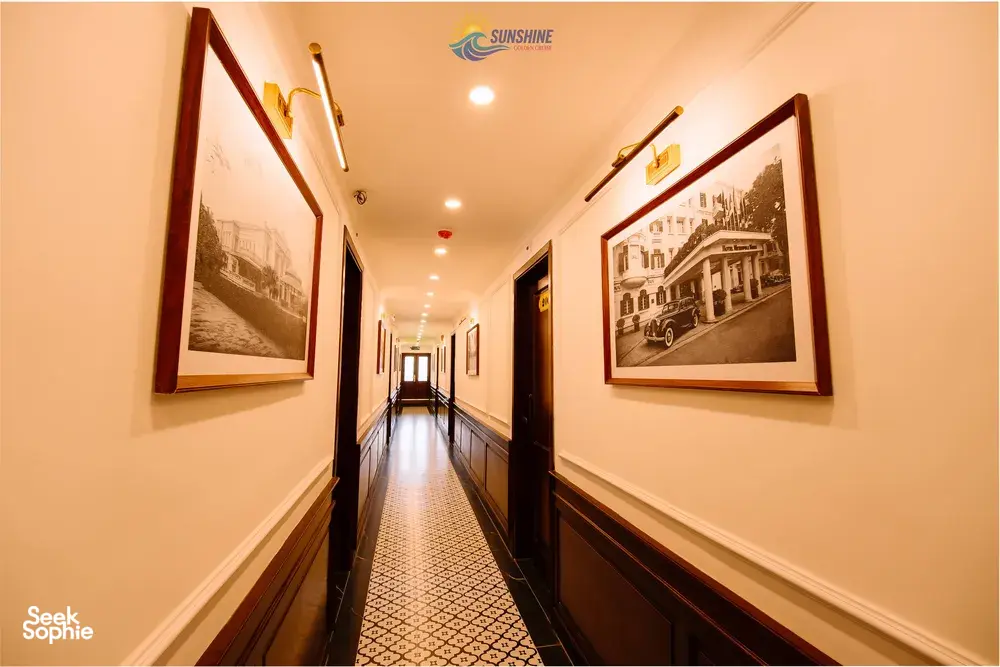 Sunshine Golden Cruises hallway corridor with framed vintage-style pictures and soft lights on a Cat Ba cruise