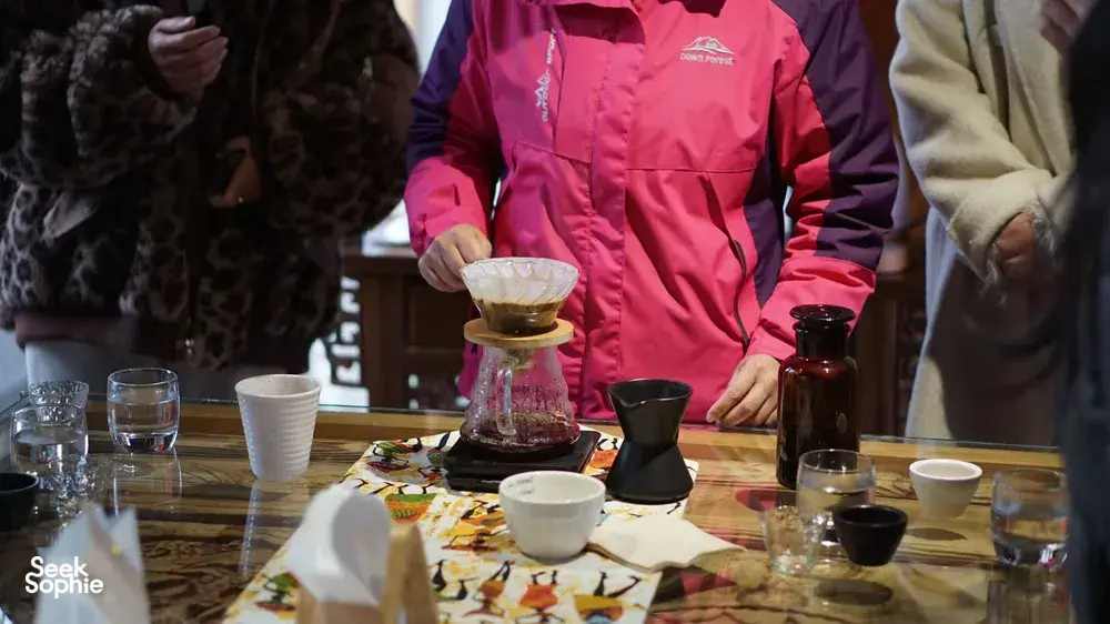 Pour-over coffee tasting at a Lijiang workshop: glass carafe, mini drippers and cups on a table as attendees prepare to sample