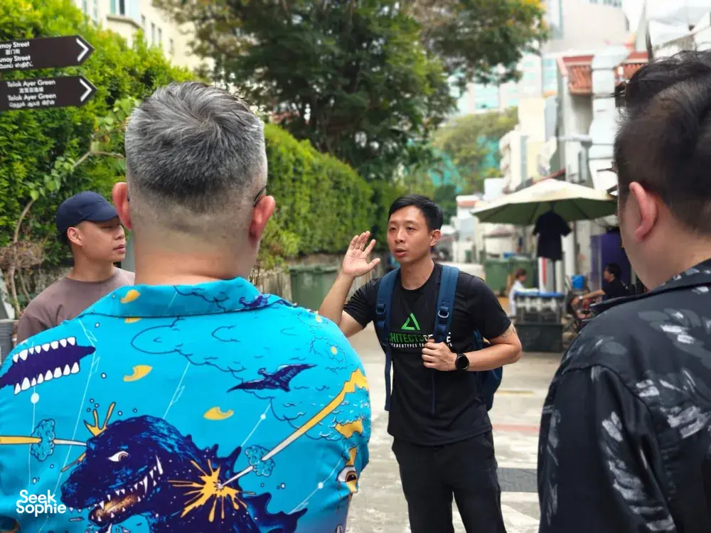 Triad Trails guide talks with visitors during a street walking tour in Singapore’s gritty underworld district
