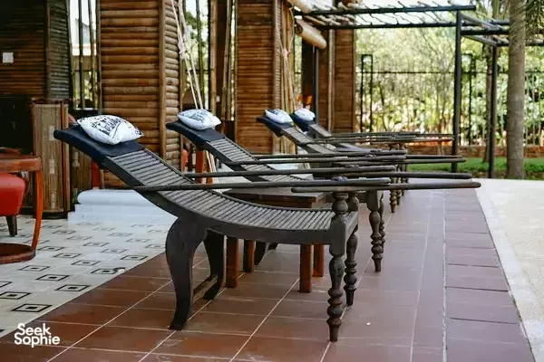 Terrace at The Island Lodge in Vietnam’s Mekong Delta with dark lounge chairs beside a wooden bungalow, for a resort stay
