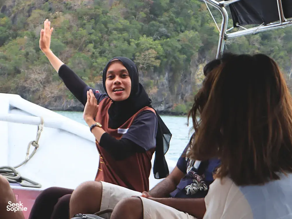 JungleWalla Langkawi naturalist gesturing on a Langkawi cruise boat, explaining the UNESCO Geopark scenery to passengers