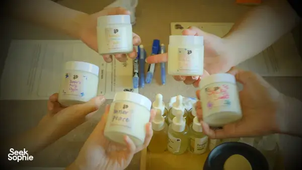 Multiple scented coco-soy candle jars held up at once after making blends at Perfume Play in Singapore candle workshop