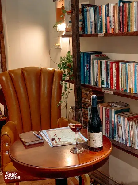 Cozy table set for a wine tasting at Chan Dat Living Room in Hoi An, with a glass, bottle, and nearby bookshelves