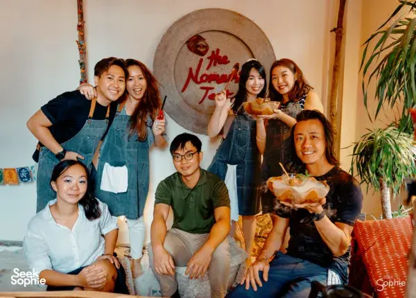 Group of participants in aprons posing with honey ice-cream cups on a cosy table during honey ice-cream workshops in Singapore