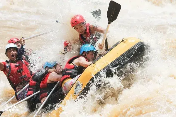 Rafters in helmets paddling an inflatable raft through choppy water on the Padas River in Sabah, guided by Xtreme Paddlers