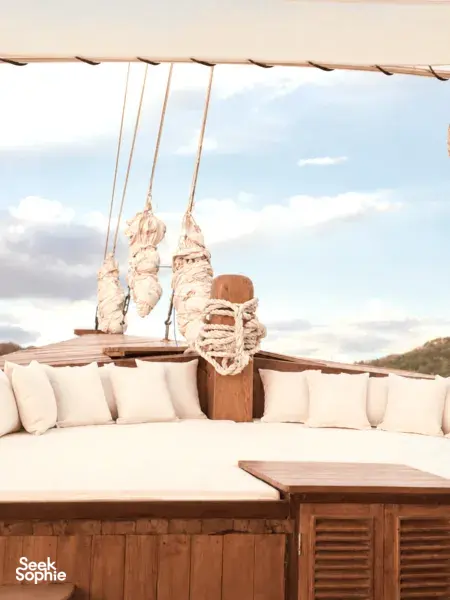 Komodo Island phinisi deck lounge with cushioned seating and hanging life jackets, part of a Travass Life 3D2N shared trip