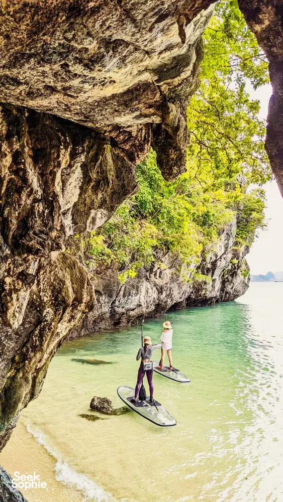 在兰卡威丹绒鲁平静水面上玩立式桨板的人们,跟随 H2Ocean Langkawi 沿着隐秘海滩划行,穿过岩石峭壁下方