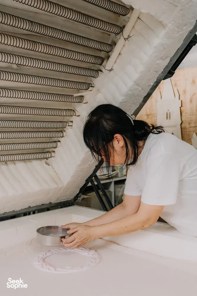 Tan Sock Fong pours and shapes materials for a glass centrepiece near the kiln wall in Singapore, workshops in Singapore