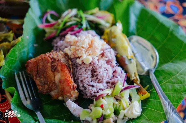 Sabahan meal served on banana leaves in Kota Kinabalu, Borneo, with rice, grilled meat, and fresh vegetables