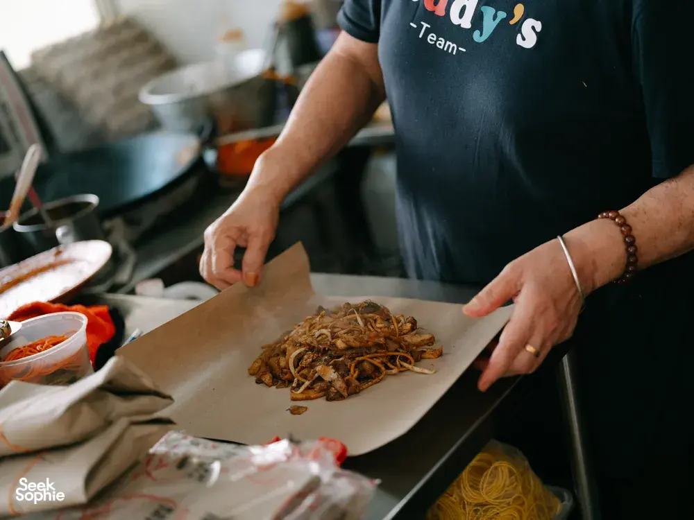 Hands spreading a mound of shredded noodles onto parchment during the Joo Chiat food tour, Singapore hidden gems