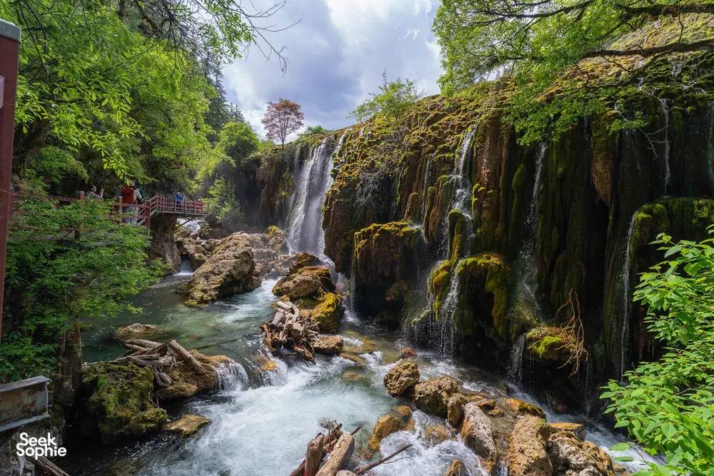 Mossy waterfall cascading into a clear river along the Shangri-La Loop in Shangri-La, guided trekking scenery