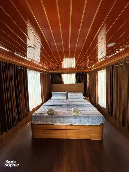Air-conditioned houseboat cabin in Tanjung Puting, Pangkalan Bun, with neatly made double bed and curtained windows