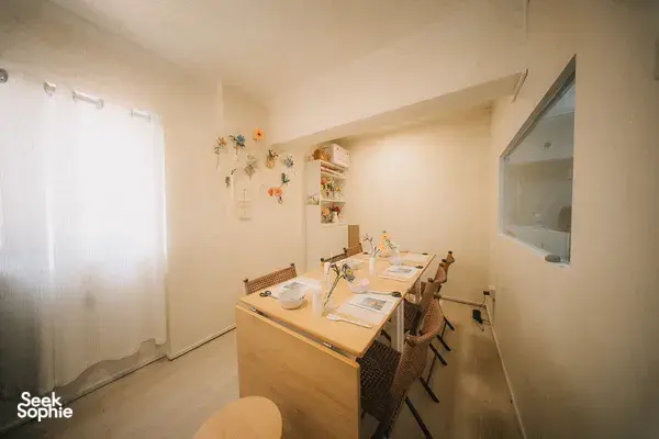 View of a small paper-flower craft studio with a central table, chairs and displays of finished blooms for workshops in Singapore