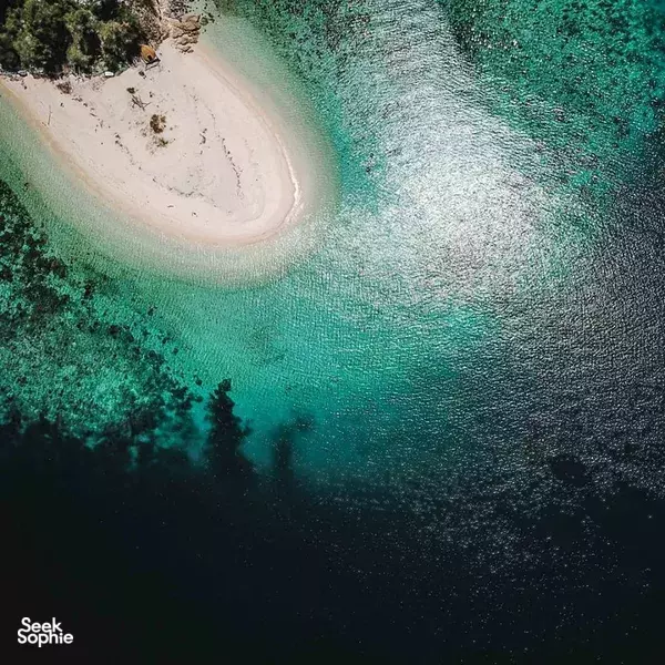 Aerial view of a small sandbar surrounded by clear turquoise water on a Komodo liveaboard in Komodo Island