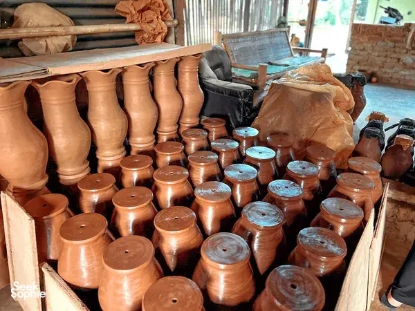 Assorted terracotta cups with blue-painted rims in a Yogyakarta pottery workshop, packed in wooden trays for drying and firing