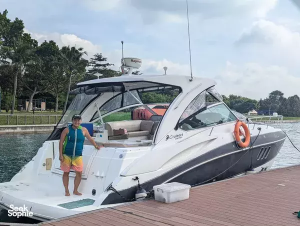 Woman posing next to an open-cabin white yacht on a Singapore marina jetty, with trees and docks in view on a 4H outing