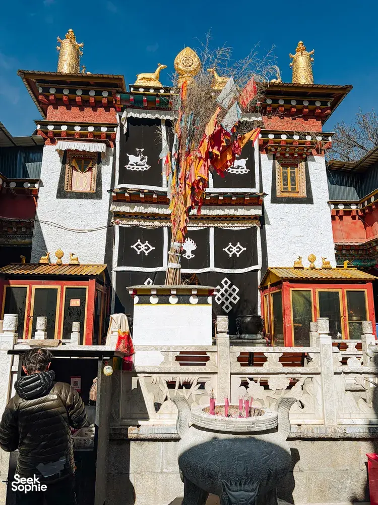 Tibetan Buddhist temple facade in Shangri-La with prayer flags and ornate gateways, bright sky over the courtyard
