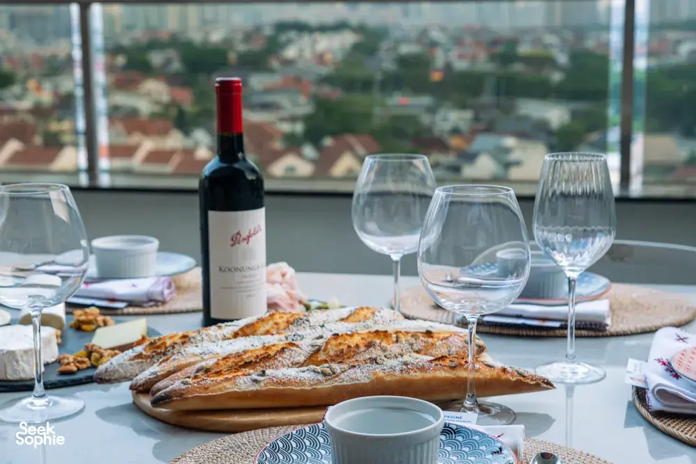 Close-up of French baguettes, a red wine bottle and glassware on a Singapore loft dinner table—private dining Singapore