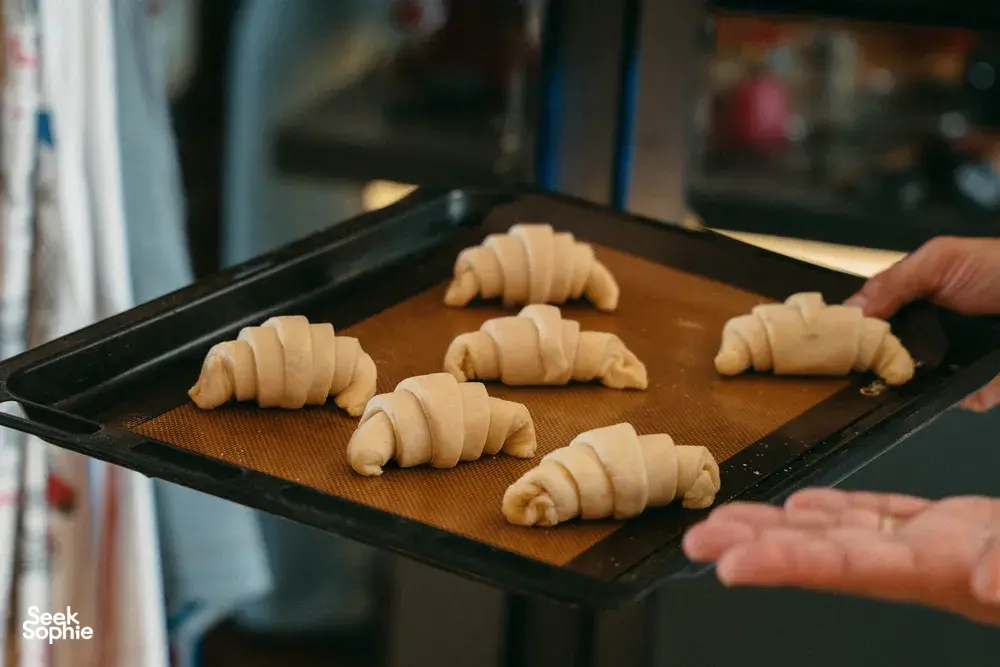 Hands arrange croissant crescents on a baking tray for French Cooking Lab home workshops in Singapore