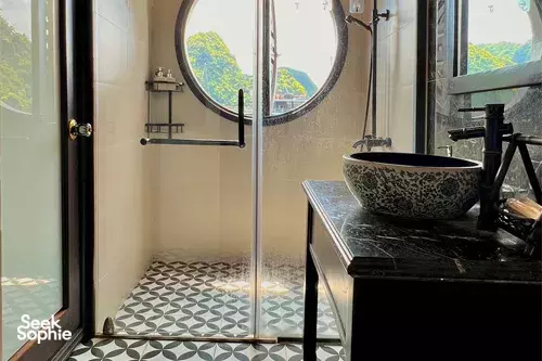 Cat Ba Ocean Cruises ensuite bathroom with a patterned sink and round porthole window for an overnight cruise in Halong Bay