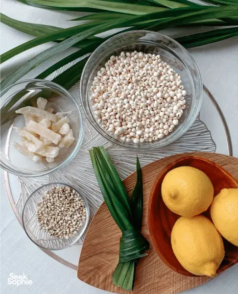 Singapore tabletop ingredient bowls for crafting TCM herbal mocktails, with lemon and green onions beside a jar of seeds