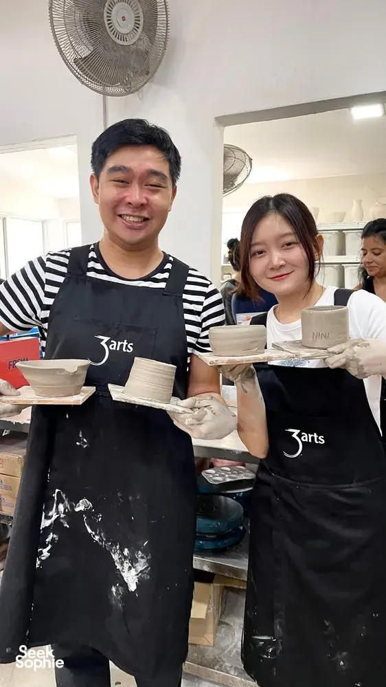 Pottery workshop at a studio in Joo Chiat Place, Singapore, with two students holding handmade ceramic pieces — workshops in Singapore