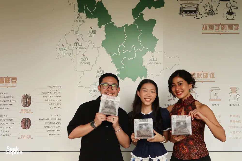Tasting participants hold up Yunnan coffee sample bags in front of a map wall during a specialty workshop in Lijiang