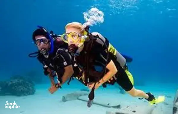 Two scuba divers with regulators and masks float underwater during Bali open-water certification training with Sanctum Dive Indonesia
