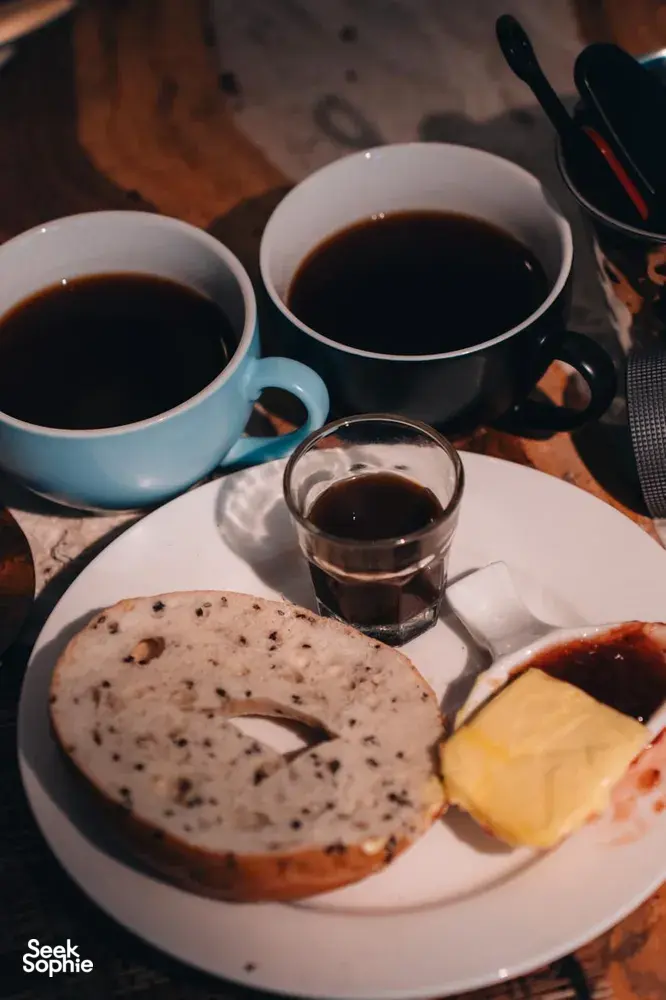 Plate of bagel with butter and cups of dark coffee at a hands-on coffee roasting and brunch experience, workshops in Singapore