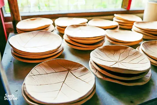 Stacked ceramic plates with etched leaf patterns arranged on a bench at Ilham Ceramic Studio, Langkawi