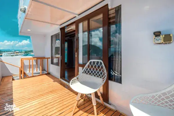 Sleek white phinisi deck balcony outside a private 3D2N Komodo cruise, with chairs overlooking Labuan Bajo