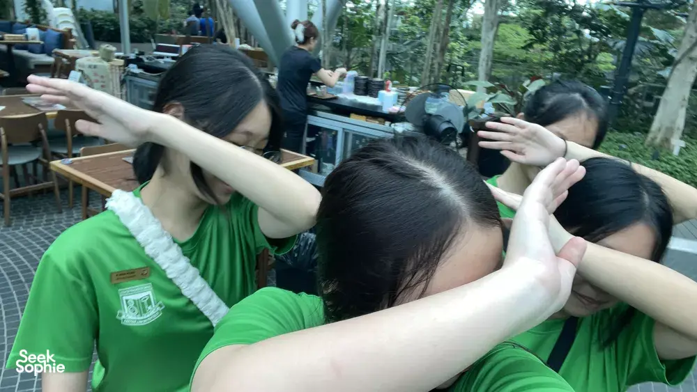 Team members in green T-shirts huddling with hands over their eyes during a team treasure hunt at Marina Central, Singapore hidden gems
